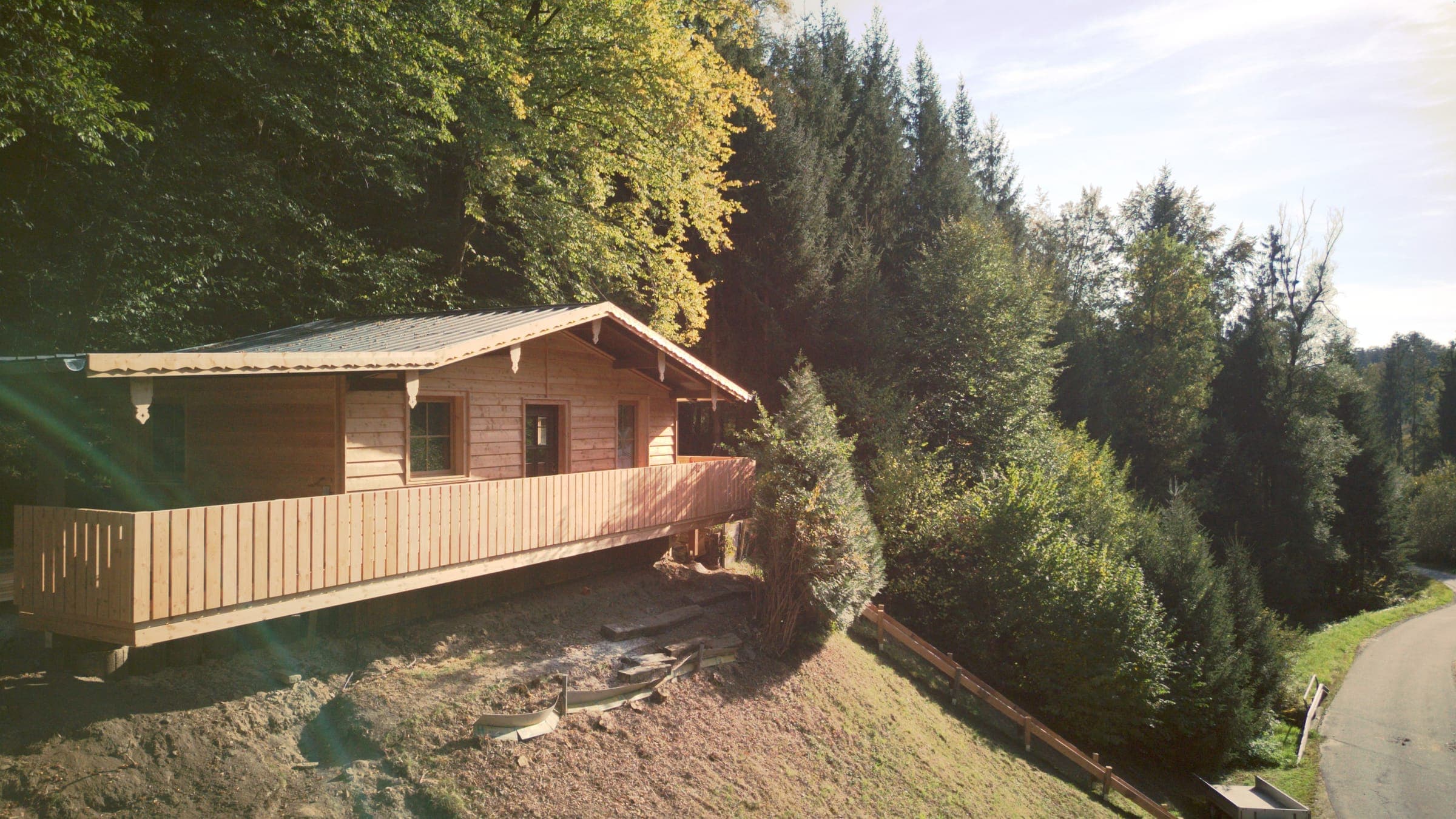 Luftbild der Hütte am Waldhang, dahinter dichter Fichtenwald und das Tal der Facklmühle