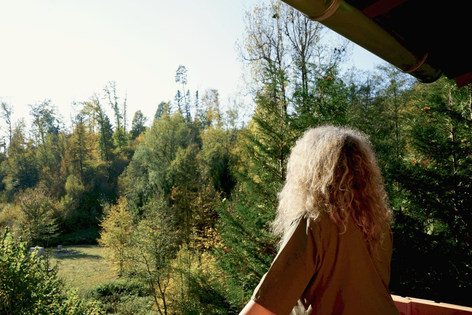 Bianca Thoma blickt vom Balkon der WALDRAUM-Hütte über das herbstliche Tal