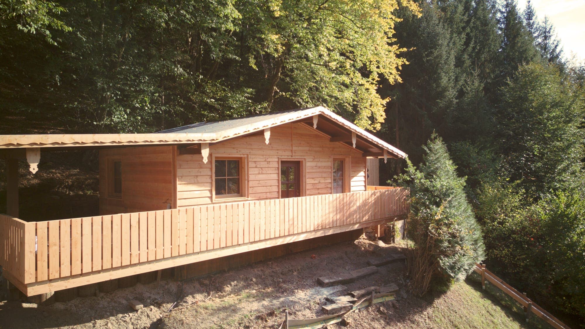 Die Hütte mit umlaufendem Holzbalkon am Waldhang